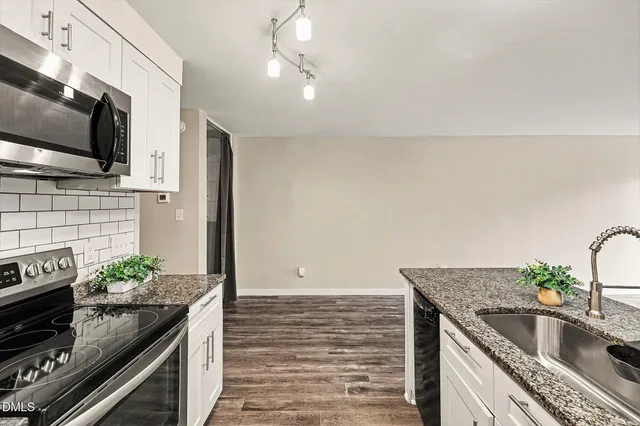 a kitchen with granite countertop white cabinets and white appliances