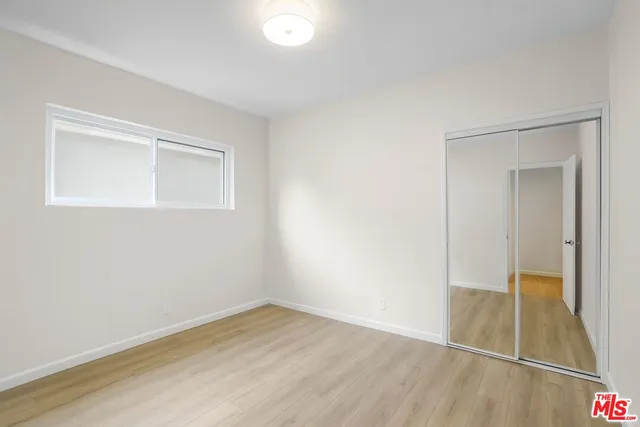 an empty room with wooden floor and mirror