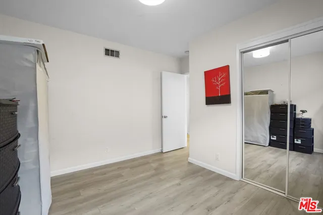 a view of a refrigerator in kitchen and an empty room with wooden floor