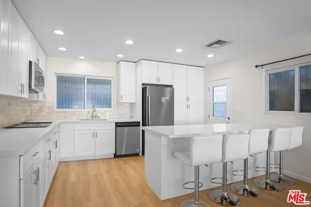 a large kitchen with stainless steel appliances kitchen island granite countertop a refrigerator and cabinets