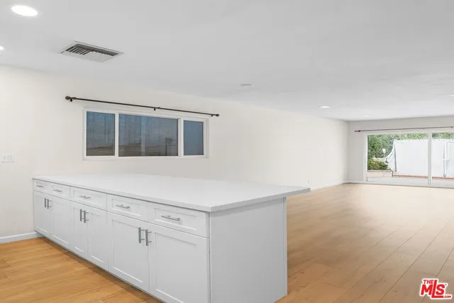 a kitchen with white cabinets and window