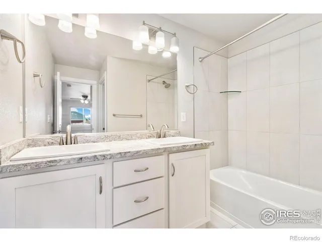 a bathroom with a granite countertop sink a mirror a bathtub and shower