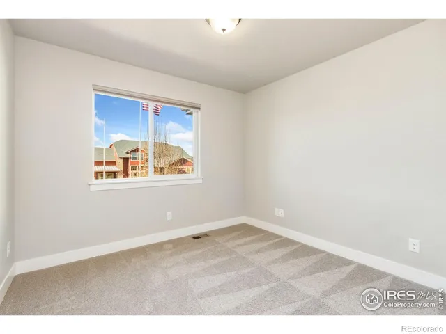 an empty room with wooden floor cabinet and windows