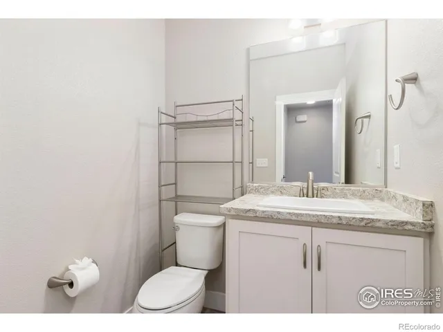 a bathroom with a granite countertop sink a toilet and a mirror