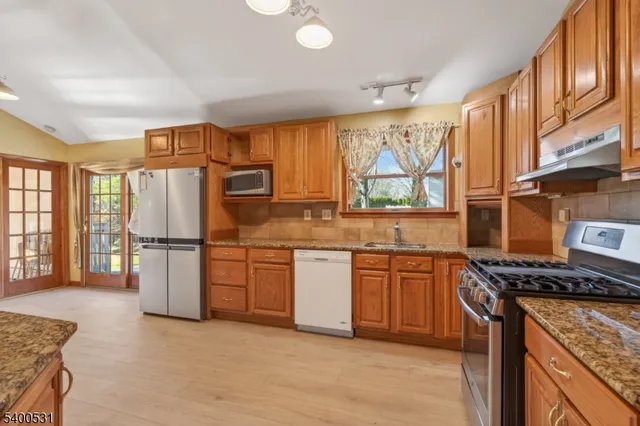 a kitchen with stainless steel appliances granite countertop a refrigerator stove top oven and sink