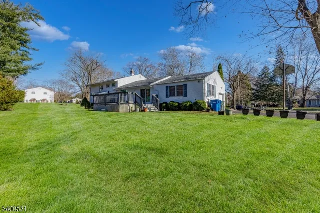 a view of a house with a big yard and large trees