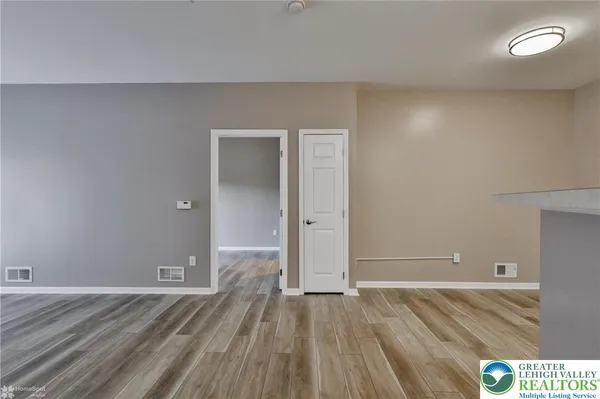 a view of an empty room with window and wooden floor