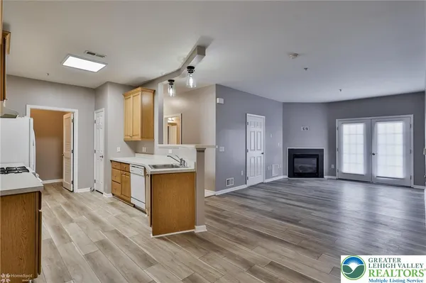 a view of a hallway with wooden floor and a kitchen