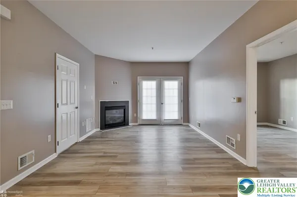 a view of an empty room with wooden floor and a fireplace