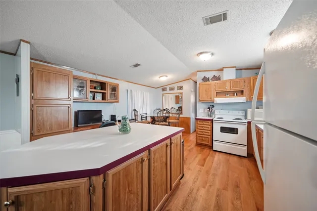 a kitchen with stainless steel appliances a stove top oven a sink dishwasher and a refrigerator with wooden floor