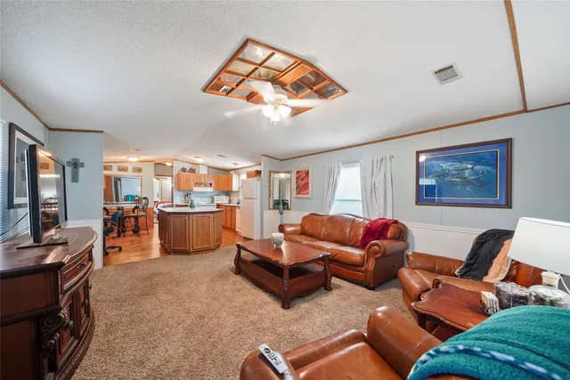 a living room with furniture a flat screen tv and kitchen view