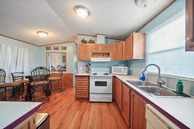 a kitchen with stainless steel appliances granite countertop wooden cabinets a sink dishwasher a stove and a refrigerator with wooden floor