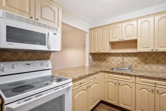 a kitchen with granite countertop white cabinets white stainless steel appliances and granite counter tops