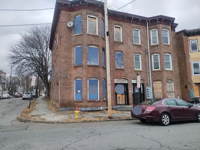 a front view of a building with lot of cars and trees
