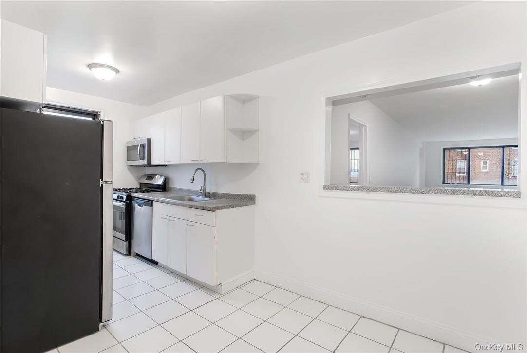 411 Bronx River Road, Unit 7F Yonkers, NY 10704 - Photo 12 of 23 a kitchen with granite countertop white cabinets and refrigerator