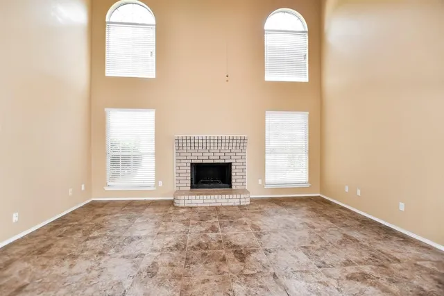 an empty room with windows and fireplace