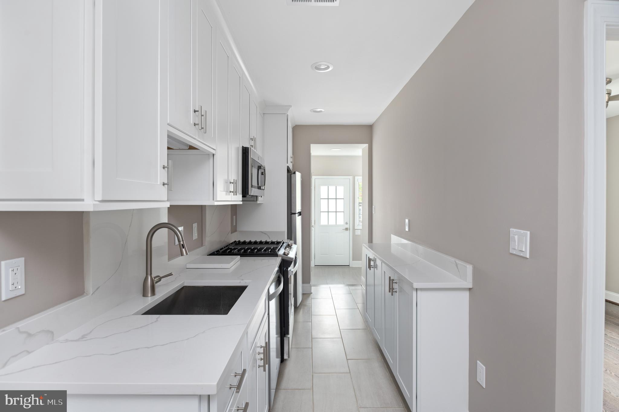 2215 40th Street Northwest, Unit 1 Washington, DC 20007 - Photo 10 of 21 a kitchen with stainless steel appliances a stove a sink and white cabinets