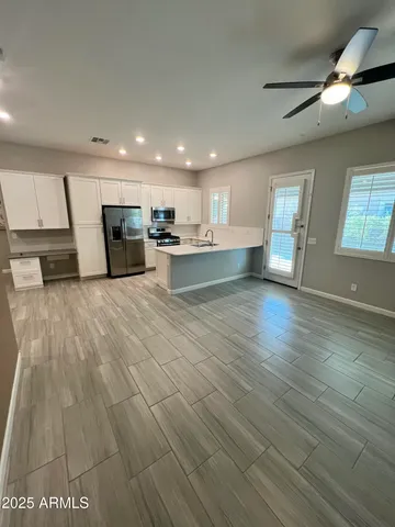 a view of a kitchen with cabinets stainless steel appliances a sink and a fireplace