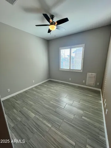an empty room with ceiling fan and window