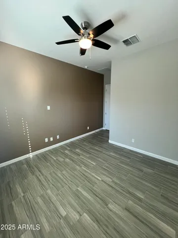 an empty room with wooden floor and ceiling fan