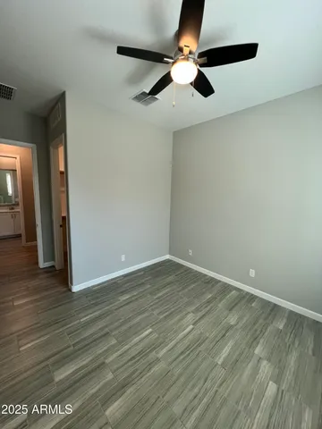 an empty room with wooden floor fan and windows