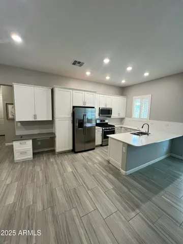 a large kitchen with stainless steel appliances a large counter top a stove and a refrigerator