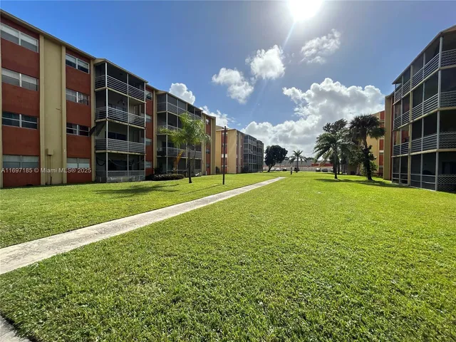 a view of a building with a big yard and large trees
