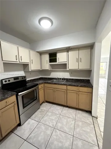 a kitchen with granite countertop a stove top oven sink and cabinets