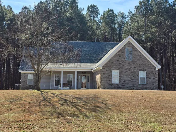 a front view of house with yard and trees in the background