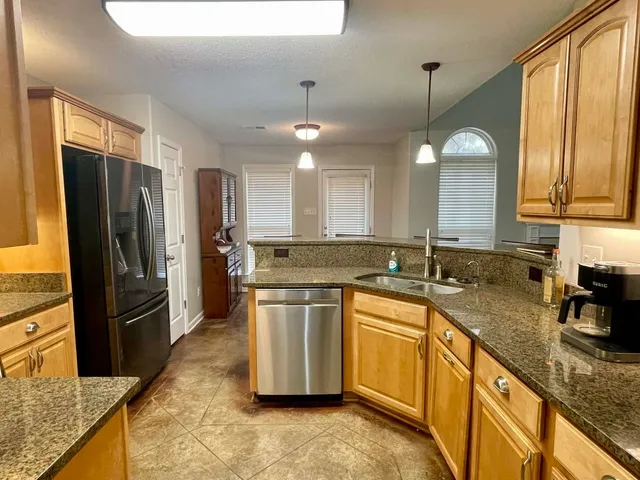 a kitchen with stainless steel appliances granite countertop a sink refrigerator and microwave
