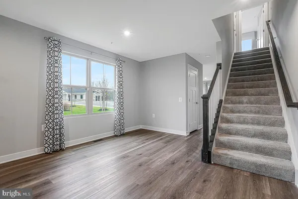 a view of an empty room with wooden floor and stairs