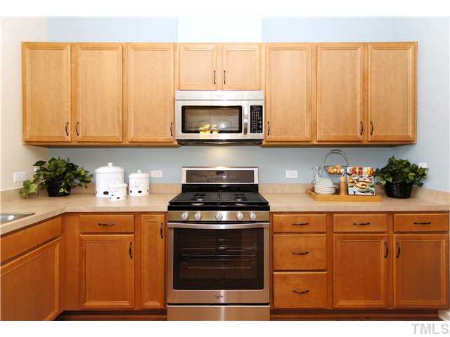 759 Wickham Ridge Road, Unit 105 Apex, NC 27539 - Photo 9 of 25 a kitchen with stainless steel appliances granite countertop a stove a sink and white cabinets