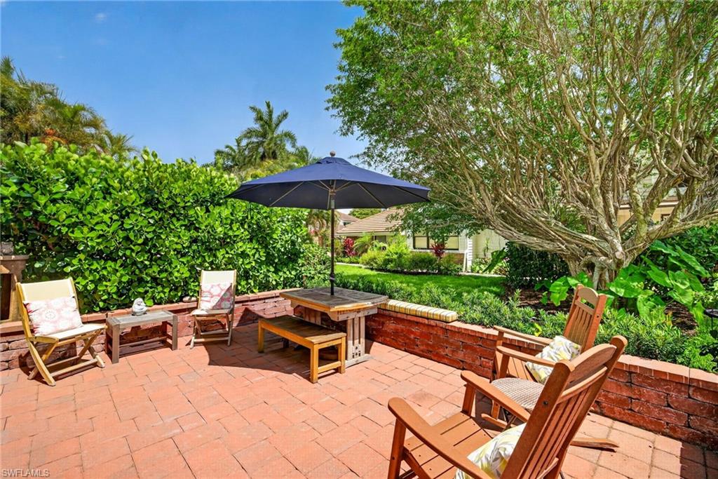 4030 Crayton Road, Unit C2 Naples, FL 34103 - Photo 30 of 32 a view of a patio with chairs and a table under an umbrella