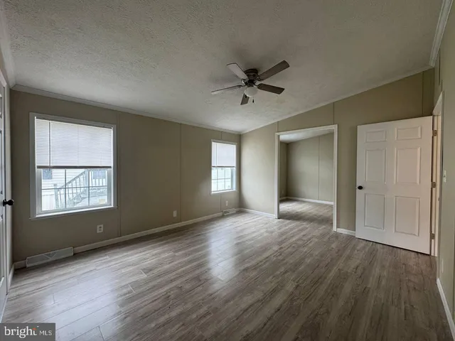 a view of empty room with wooden floor and fan
