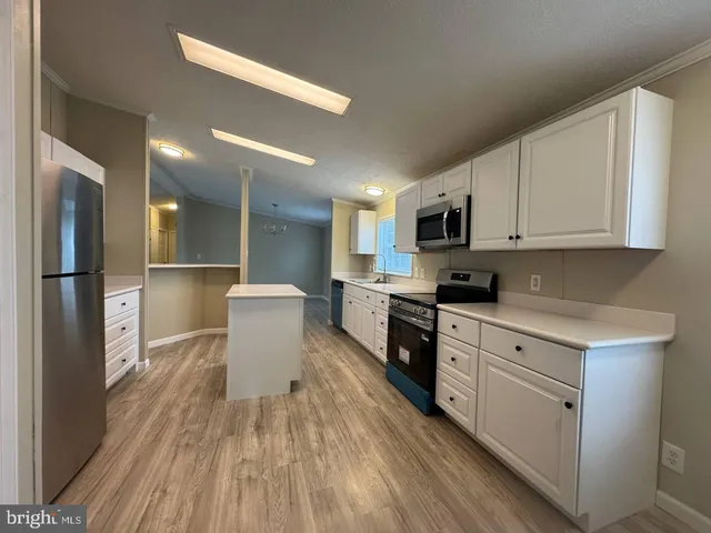 a kitchen with stainless steel appliances granite countertop a refrigerator a stove top oven a sink dishwasher and white cabinets with wooden floor