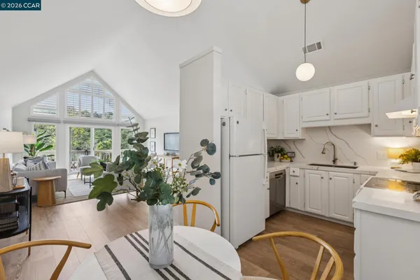 a kitchen with stainless steel appliances kitchen island granite countertop a refrigerator a stove a sink dishwasher and white cabinets with wooden floor