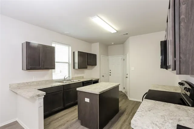 a kitchen with a sink and a stove top oven with wooden floor