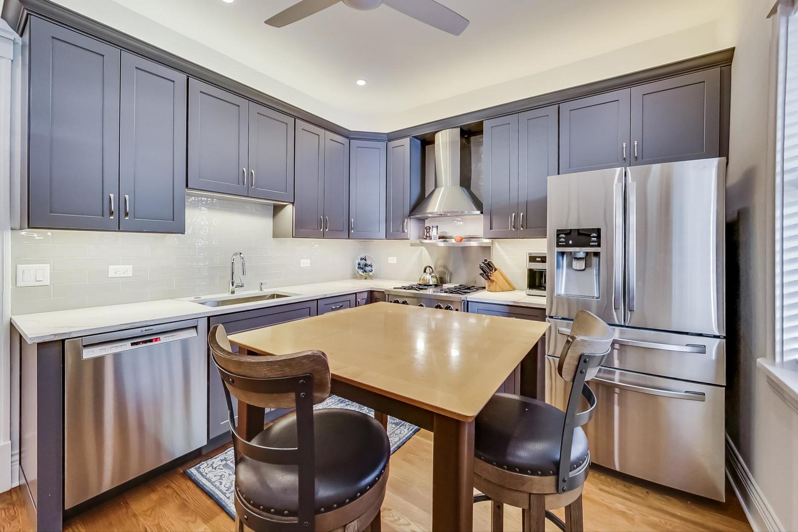 1934 West Grace Street Chicago, IL 60613 - Photo 10 of 34 a kitchen with stainless steel appliances a refrigerator a sink a stove a dining table and chairs