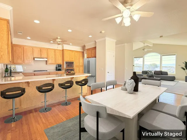 a kitchen with stainless steel appliances kitchen island granite countertop a stove a sink a dining table and chairs with wooden floor