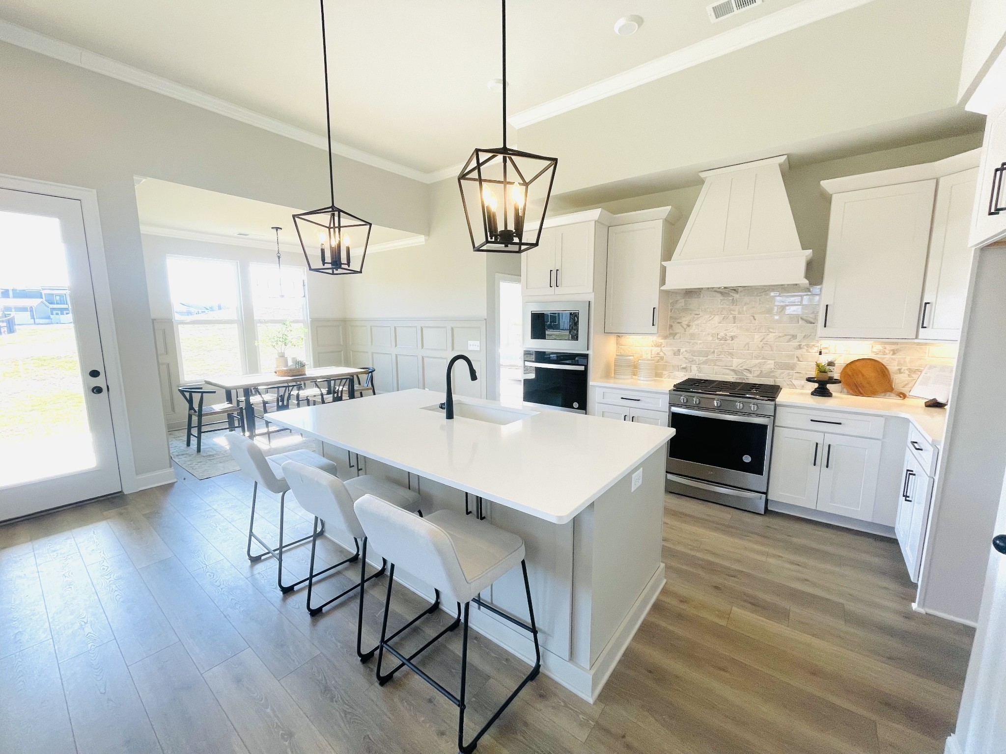 3033 Shandor St Spring Hill Spring Hill, TN 37174 - Photo 18 of 70 a kitchen with stainless steel appliances a dining table a stove a sink dishwasher and white cabinets with wooden floor
