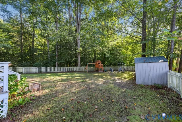 a view of a backyard with plants and wooden fence