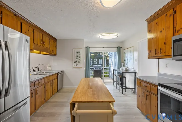 a kitchen with stainless steel appliances granite countertop a refrigerator a stove top oven a sink and dishwasher