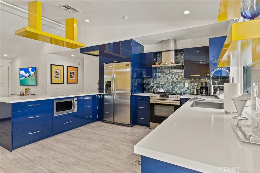 68190 Galardo Road Cathedral City, CA 92234 - Photo 10 of 24 a kitchen with stainless steel appliances wooden cabinets a center island and a stove