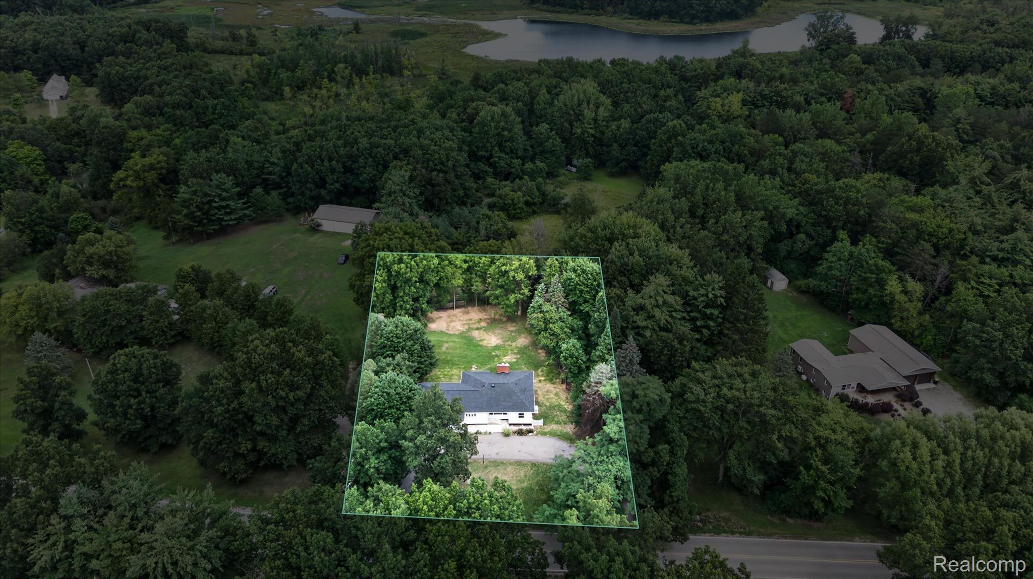 11403 White Lake Road Fenton, MI 48430 - Photo 36 of 36 Aerial perspective of a single-family residence featuring a white exterior and a dark roof, surrounded by mature trees