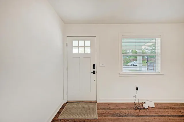 a view of an empty room with wooden floor and a window