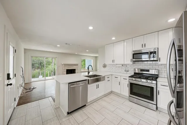 a kitchen with white cabinets stainless steel appliances and a window
