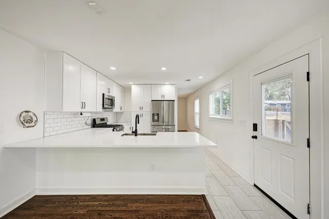 a large white kitchen with kitchen island a counter top space a sink and cabinets