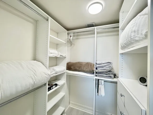 a room with a closet and white wooden cabinets