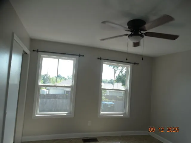 an empty room with a ceiling fan and carpet