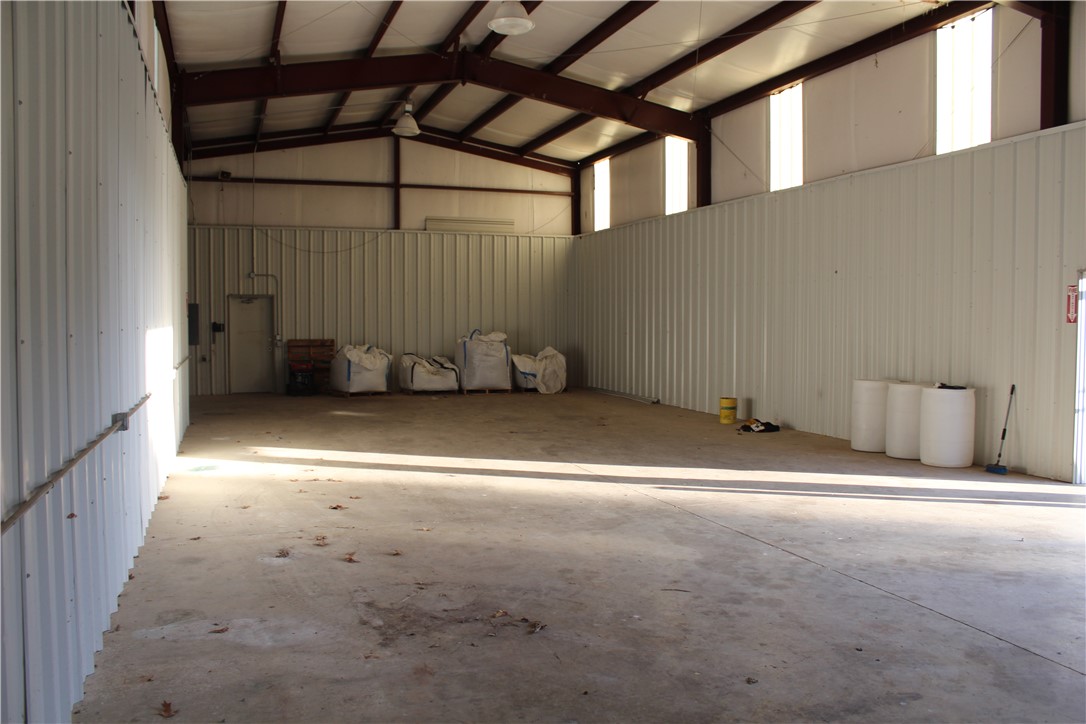 158 Ragon Road Tilly, AR 72679 - Photo 25 of 51 Spacious industrial interior featuring a concrete floor, corrugated metal walls, exposed steel beam construction, and overhead lighting fixtures